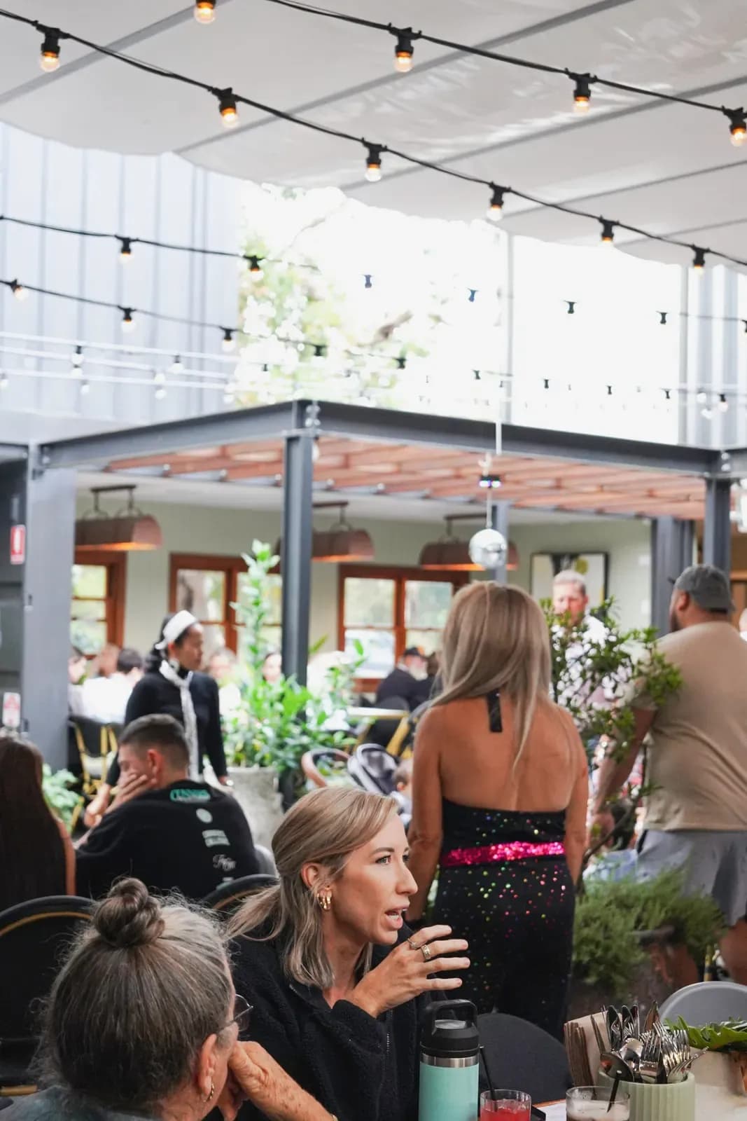 Guests dining in the courtyard at The 383 Wooli under string lights